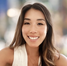 a woman is smiling and wearing a white tank top