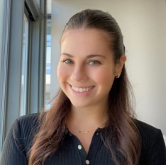 a woman in a black shirt is smiling in front of a window .