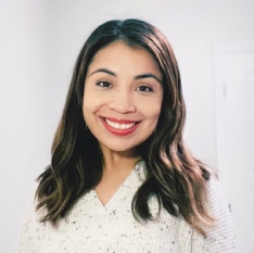 a woman wearing a white shirt and red lipstick is smiling for the camera .