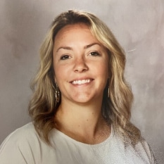 a woman in a white shirt is smiling for the camera .