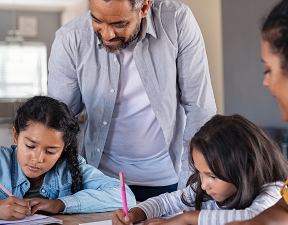 a man and woman are helping two young girls with their homework